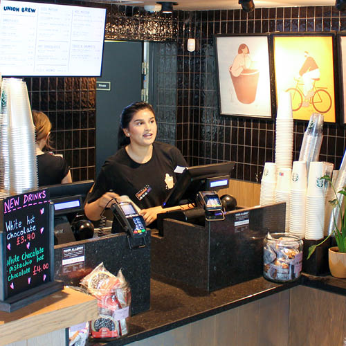 Person serving coffee in a Starbucks counter